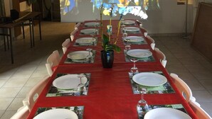 A conference room with a long table set for a meeting, a projector screen displaying a floral image, and a brick wall. - 2 gîtes groupable from 4 to 15 pers for 2- 4 -6 to 32 pers 15km from ARRAS (Arras)