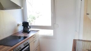 A compact kitchen with a stove, oven, and a window providing natural light. - Vacation home Chiara in Ilfeld, idyllic directly in the countryside!!!  (Harztor)