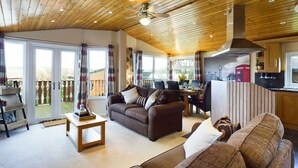 A spacious living area with a wooden ceiling, a dining table, and a kitchen area. - Lovely 3-bed House in Carnforth (Carnforth)