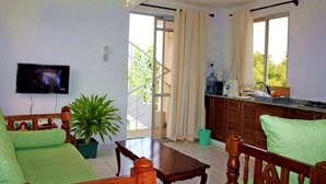A living area with a sofa, a wooden coffee table, a television, and a potted plant. - Stay.Plus Nyandarua Road Apartment Nyali (Mombasa)