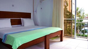 A bedroom with a wooden bed, a green bedspread, and a view of a balcony with plants. - Stay.Plus Nyandarua Road Apartment Nyali (Mombasa)