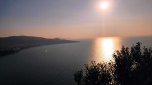 A calm body of water reflecting the sun, surrounded by hills and trees. - Apartment Lucia (Vico Equense)