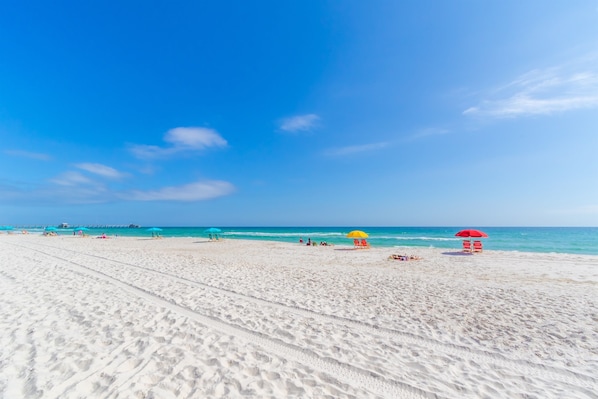 A wide sandy beach with clear blue skies and calm waters.