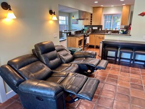 Eine moderne Küche mit Holzausbau, einer Essecke mit Bar und einem ledernen Ecksofa.
