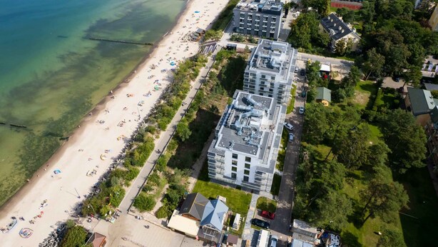 An aerial view of a coastal area with a beach, buildings, and greenery. - Air-conditioned Studio | Balcony, Gym and 50 m to the Beach (Mielno)