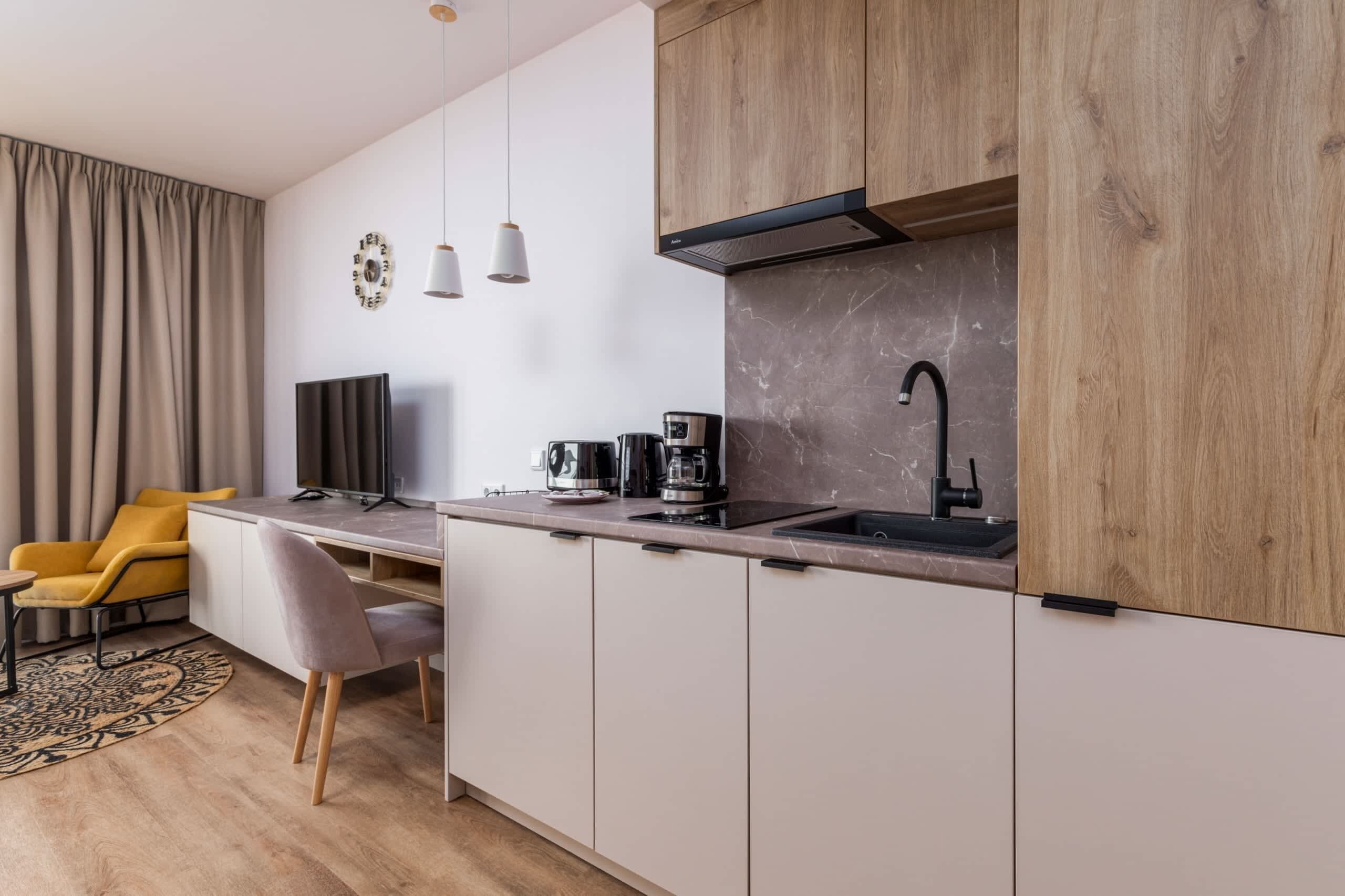 Une cuisine moderne équipée d’une cuisinière intégrée, d’une machine à café et d’un évier. On y trouve également un coin repas avec une chaise et une table.
