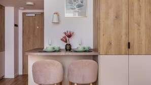 Una cocina moderna con un mueble de madera, una obra de arte enmarcada y dos sillas.