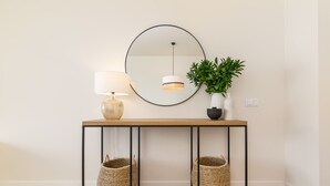 A console table with a round mirror, a lamp, and a potted plant.