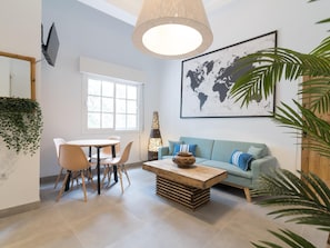 A modern living room with a round table, chairs, a sofa, a coffee table, and a world map on the wall.