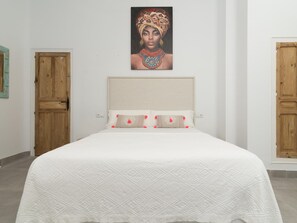 Un dormitorio con una cama grande, una puerta de madera y un cuadro en la pared.