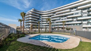 Een modern hotel met een gebogen gevel, een zwembad en palmbomen.