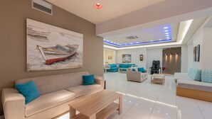 Una sala de estar moderna con un sofá color beige, una mesa de centro de madera y un cuadro de un barco en la pared.