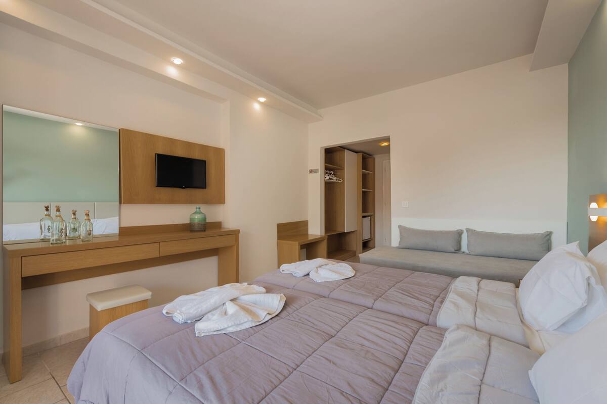 A bedroom with a large bed, a wooden desk with a TV, and a walk-in closet.