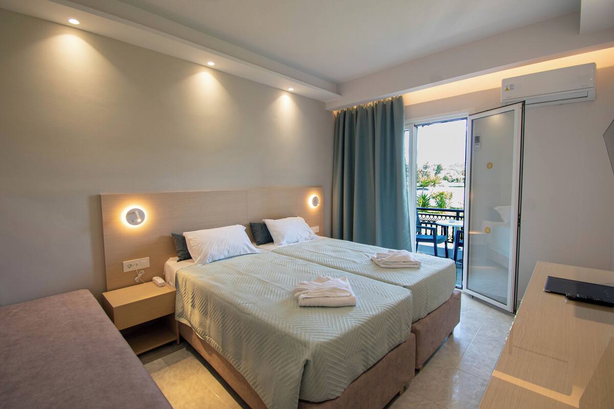 A modern hotel room with a large bed, bedside tables, a desk, and a balcony with a view.