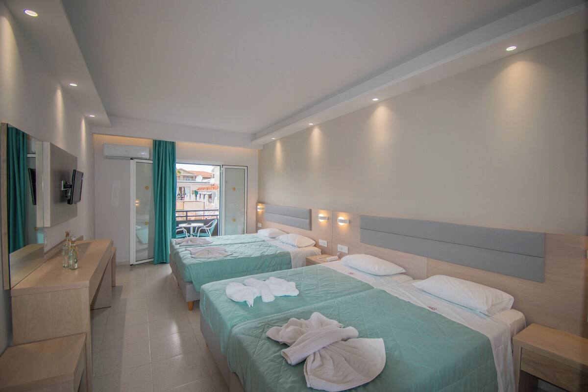A hotel room with two beds, a desk, and a bathroom visible through an open door.