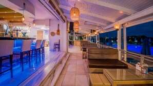 Zona de bar con asientos, vista a la piscina y barra con grifo de cerveza.