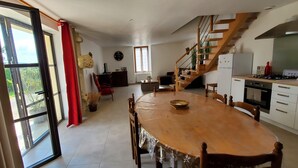 Eine geräumige Küche mit einem Holzespeise Tisch, einer Treppe und einem großen Fenster mit roten Vorhängen.