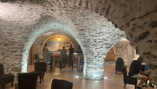 Interior de paredes de piedra con zonas de estar y una barra.