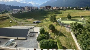 Vista de una zona montañosa con edificios, un campo verde y una cancha deportiva.