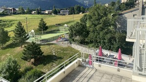 Vista de un paisaje montañoso con un parque infantil, una iglesia y edificios residenciales.