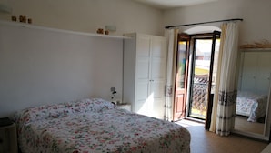 A bedroom with a bed, a nightstand, a wardrobe, and a sliding glass door leading to an outdoor area.
