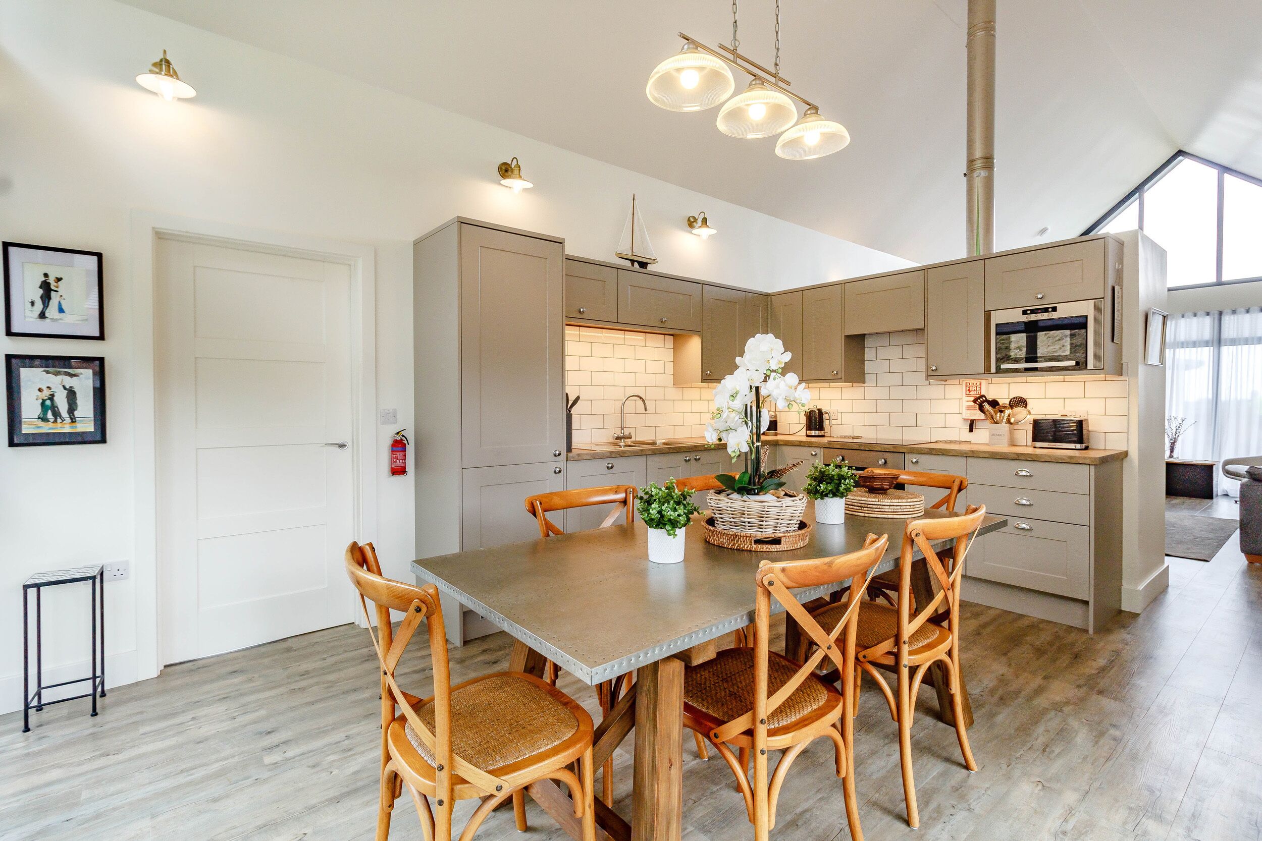 Una cocina moderna con una isla central, sillas de madera y una mesa de comedor.