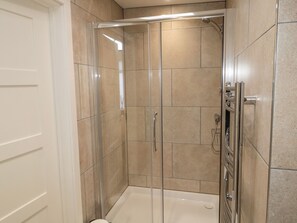 Eine begehbare Dusche mit Glastür, geflieste Wände und einer Badewanne.