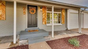 A residential house with a grey facade, a dark front door, and a porch with steps. - Private Chic 2br | 10 min to Downtown| Fast Wifi (Denver)