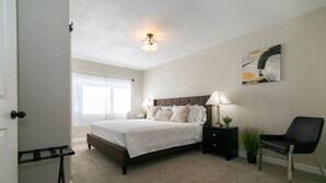 A bedroom with a bed, bedside tables, a chair, a window, and a ceiling light. - Private Chic 2br | 10 min to Downtown| Fast Wifi (Denver)