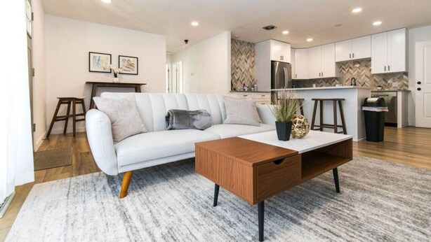A modern living room with a sofa, coffee table, and a kitchen in the background. - Private Chic 2br | 10 min to Downtown| Fast Wifi (Denver)