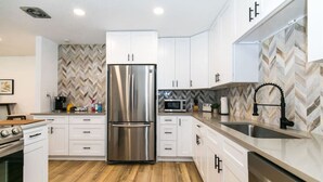 A modern kitchen with white cabinets, a stainless steel refrigerator, a microwave, and a sink with a black faucet. - Private Chic 2br | 10 min to Downtown| Fast Wifi (Denver)