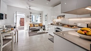 A modern kitchen with white cabinetry, a central island, and a dining area with a white table and chairs.