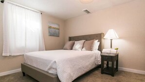 A bedroom with a bed, a nightstand, a lamp, and a painting on the wall. - Cozy 2bd |10 min to Downtown Denver | Fast Wifi (Denver)