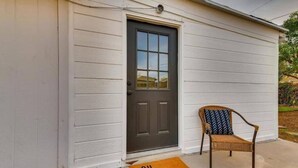 A house with a dark front door, a wicker chair with a patterned cushion, and a doormat with "OH HELLO" written on it. - Cozy 2bd |10 min to Downtown Denver | Fast Wifi (Denver)