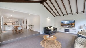 A spacious living area with a modern kitchen, a large flat-screen TV, and a cozy seating arrangement.