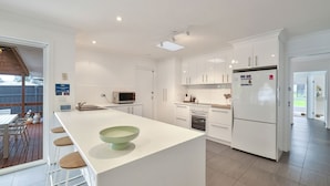A modern kitchen with white cabinetry, a central island, and a dining area with a wooden table and chairs.