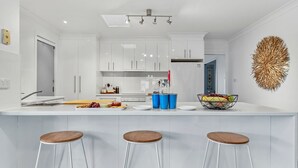 A modern kitchen with white cabinets, a central island with stools, and a decorative wall piece.