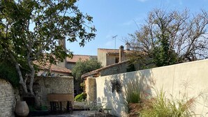 A swimming pool with a wooden deck, surrounded by stone walls and vegetation.