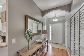 Stylish hallway with a console table, mirror, and decorative lamp, leading to a door with white shutters.