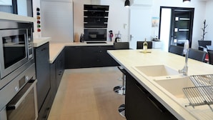 A modern kitchen with a large island, stainless steel appliances, and pendant lighting.