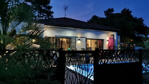 A modern house with a swimming pool, surrounded by greenery.