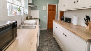 A compact kitchen with a microwave, sink, and wooden countertop. - Cornerways, 8 North Lane (York)