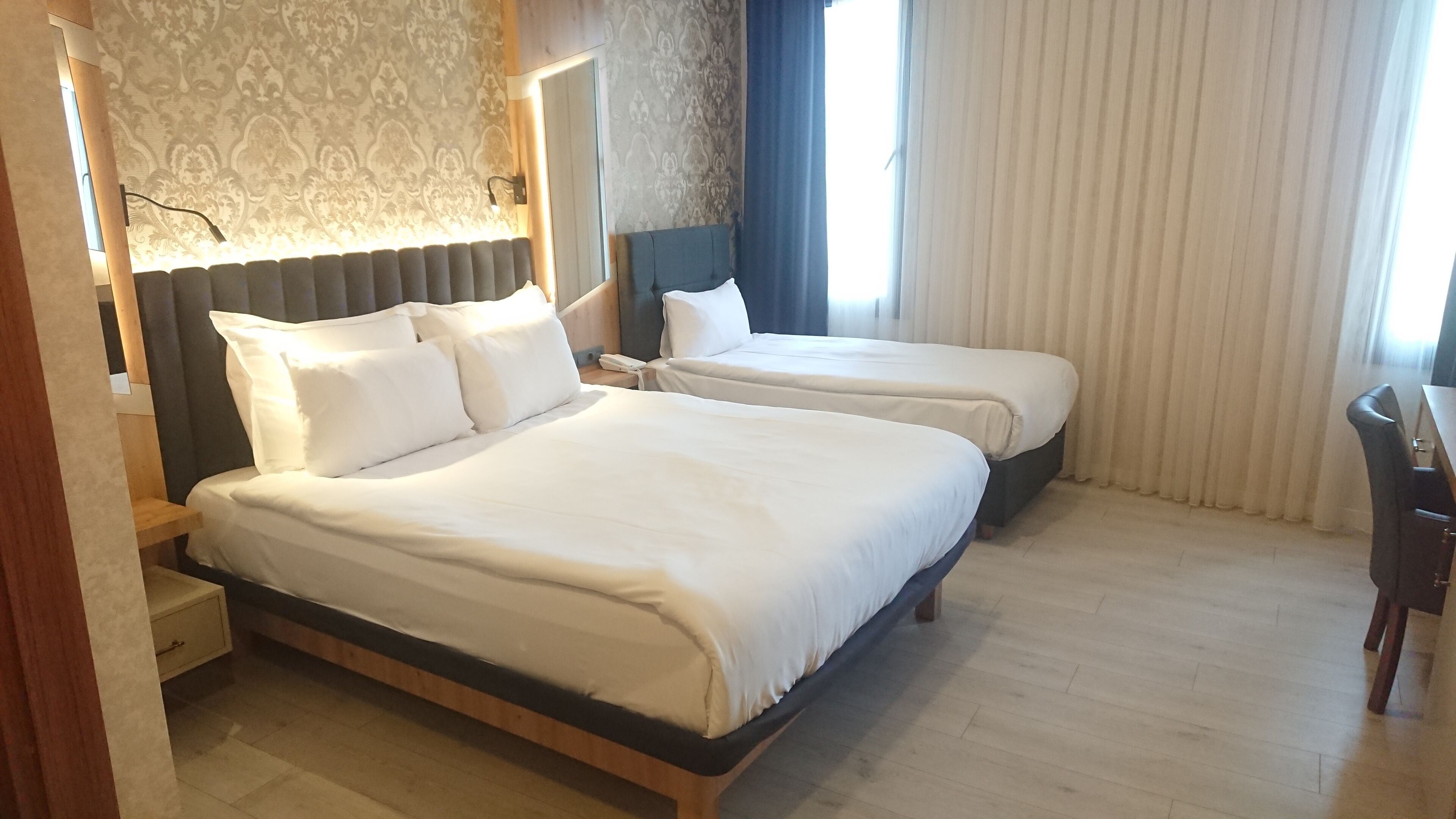 A hotel room with two beds, a desk, and a chair.