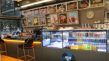 A cafe with a counter, seating area, menu boards, and a beverage display.