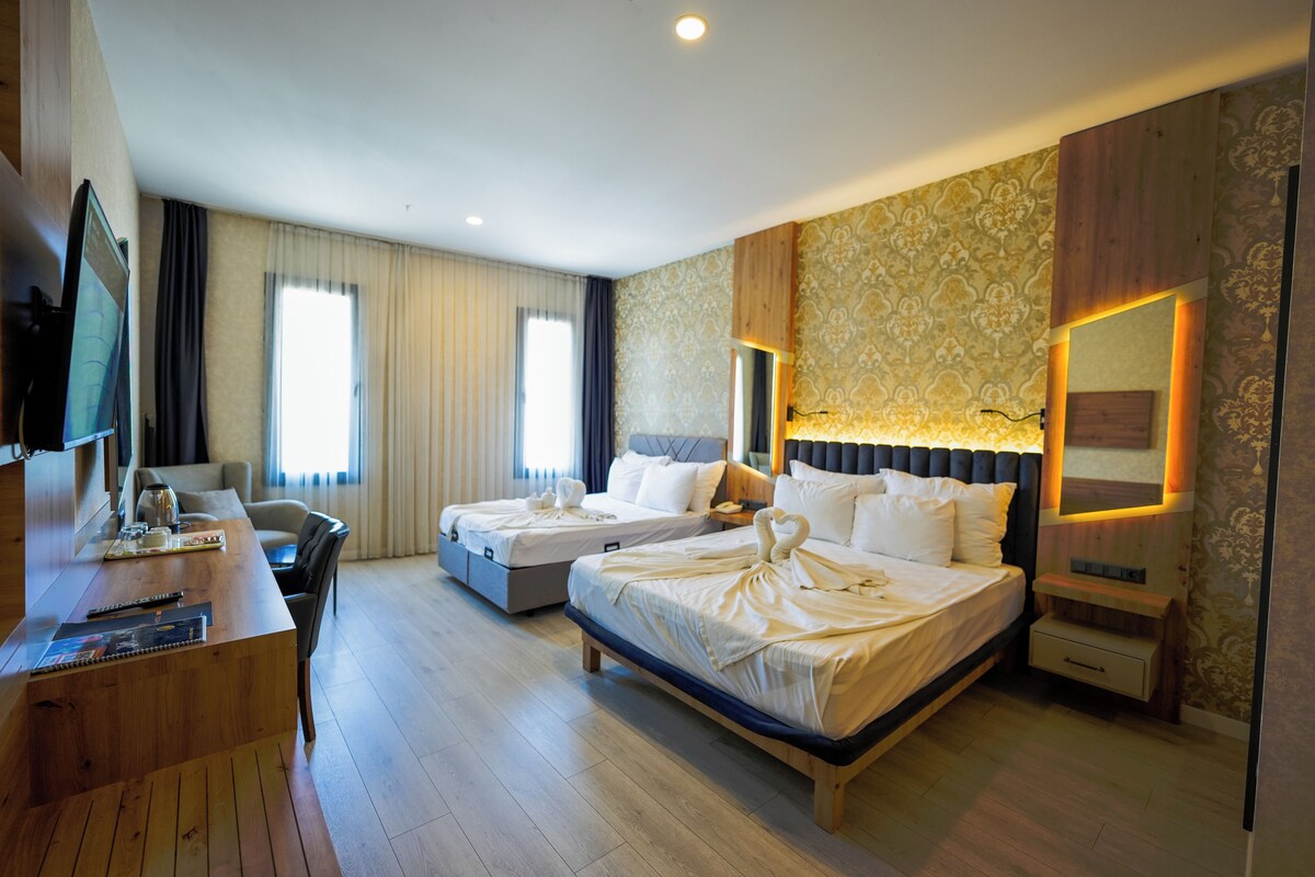 Une chambre d’hôtel avec deux lits, un bureau, une télévision et une grande fenêtre.