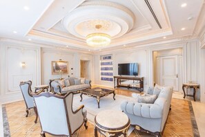 A luxurious living room with ornate ceiling details, a chandelier, and a large flat-screen TV. - Savitsky Plaza (Samarkand)
