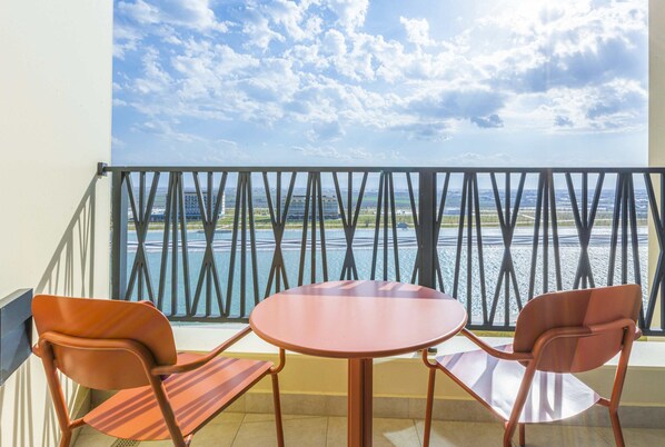 A balcony with two chairs and a table, overlooking a body of water and buildings. - Savitsky Plaza (Samarkand)
