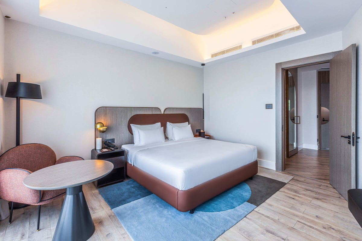 A modern hotel room with a large bed, a round table, and a chair.