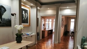 A modern interior with a wooden herringbone floor, a dining area with a table and chairs, and a kitchen visible through an open doorway. - Etoile-Champs Elysée (Paris)