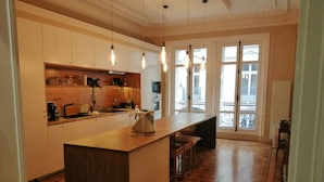 A modern kitchen with wooden flooring, a central island, and pendant lighting. - Etoile-Champs Elysée (Paris)